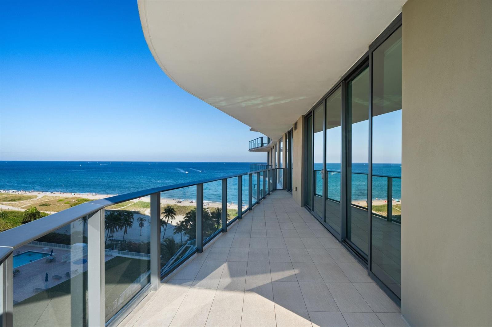 A long, tiled balcony with glass railings overlooks a sandy beach and the ocean — 730 N Ocean Boulevard # 801, Pompano Beach FL 33062, POMPANO BEACH, FL