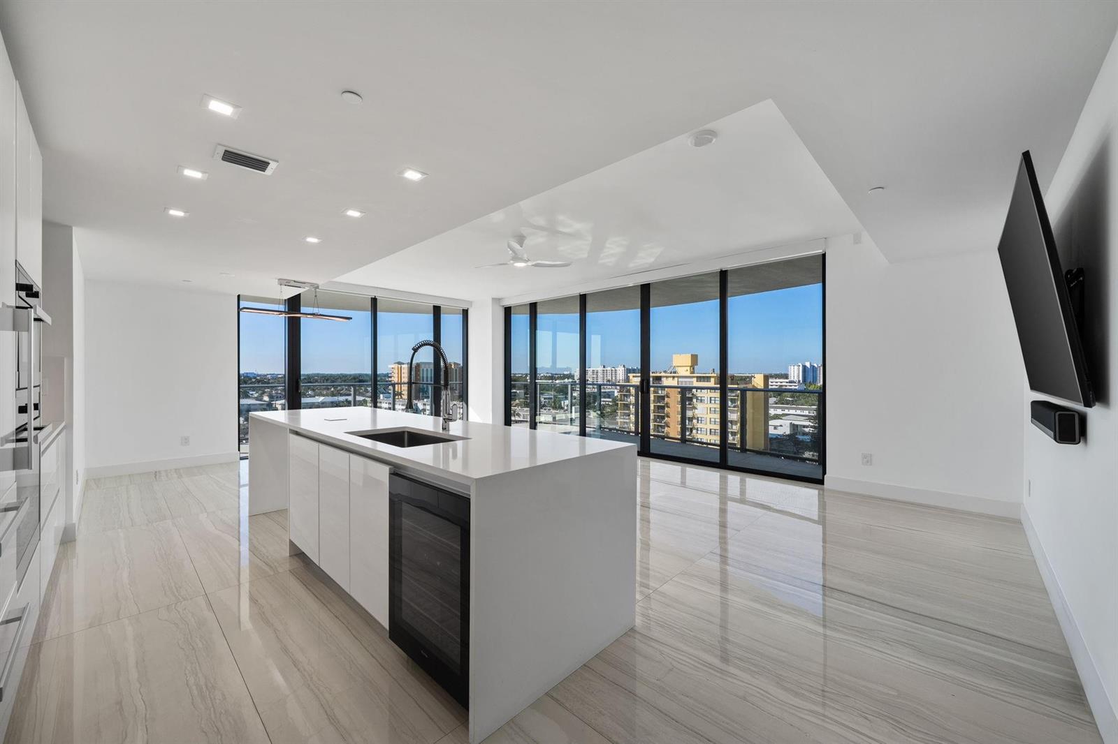 A modern kitchen with a white island, glossy tile floors, and floor-to-ceiling windows — 730 N Ocean Boulevard # 801, Pompano Beach FL 33062, POMPANO BEACH, FL