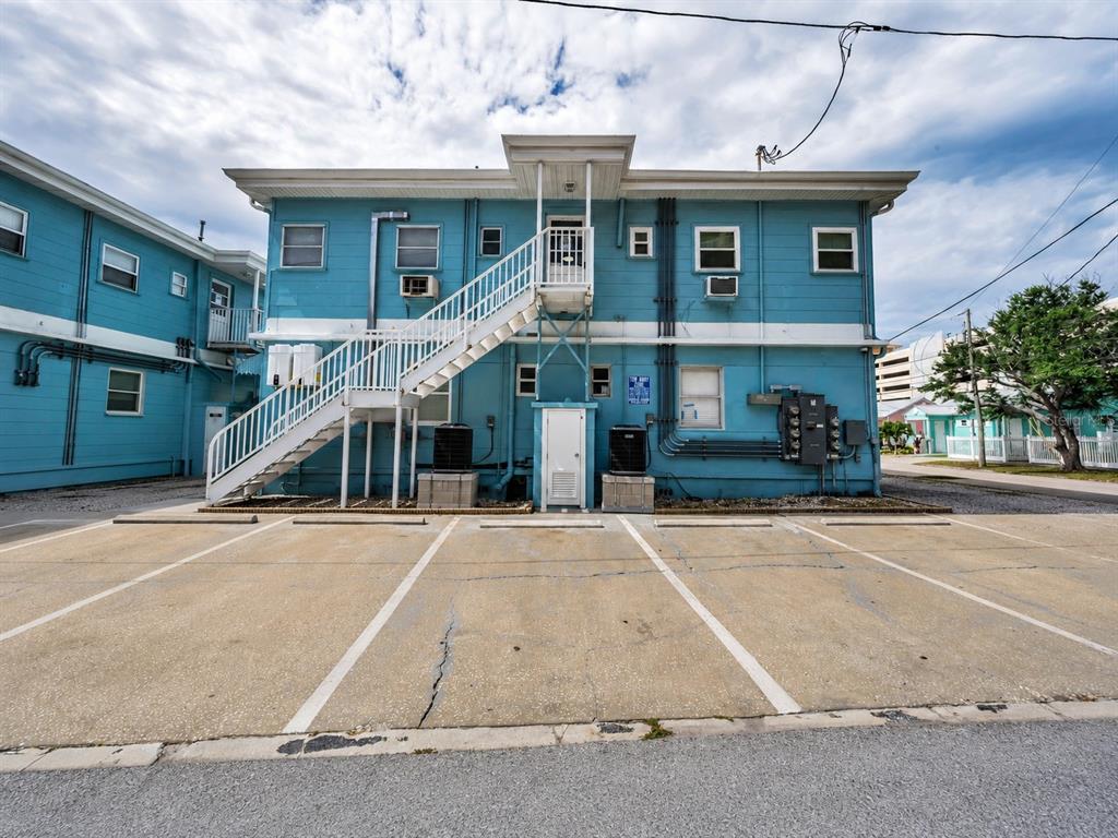 The exterior of a blue two-story apartment building features an outdoor staircase and parking spaces — 483 E SHORE DRIVE UNIT A4, CLEARWATER BEACH, FL