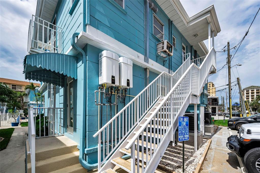 A two-story blue building features an exterior staircase and a paved parking lot in front — 483 E SHORE DRIVE UNIT A4, CLEARWATER BEACH, FL