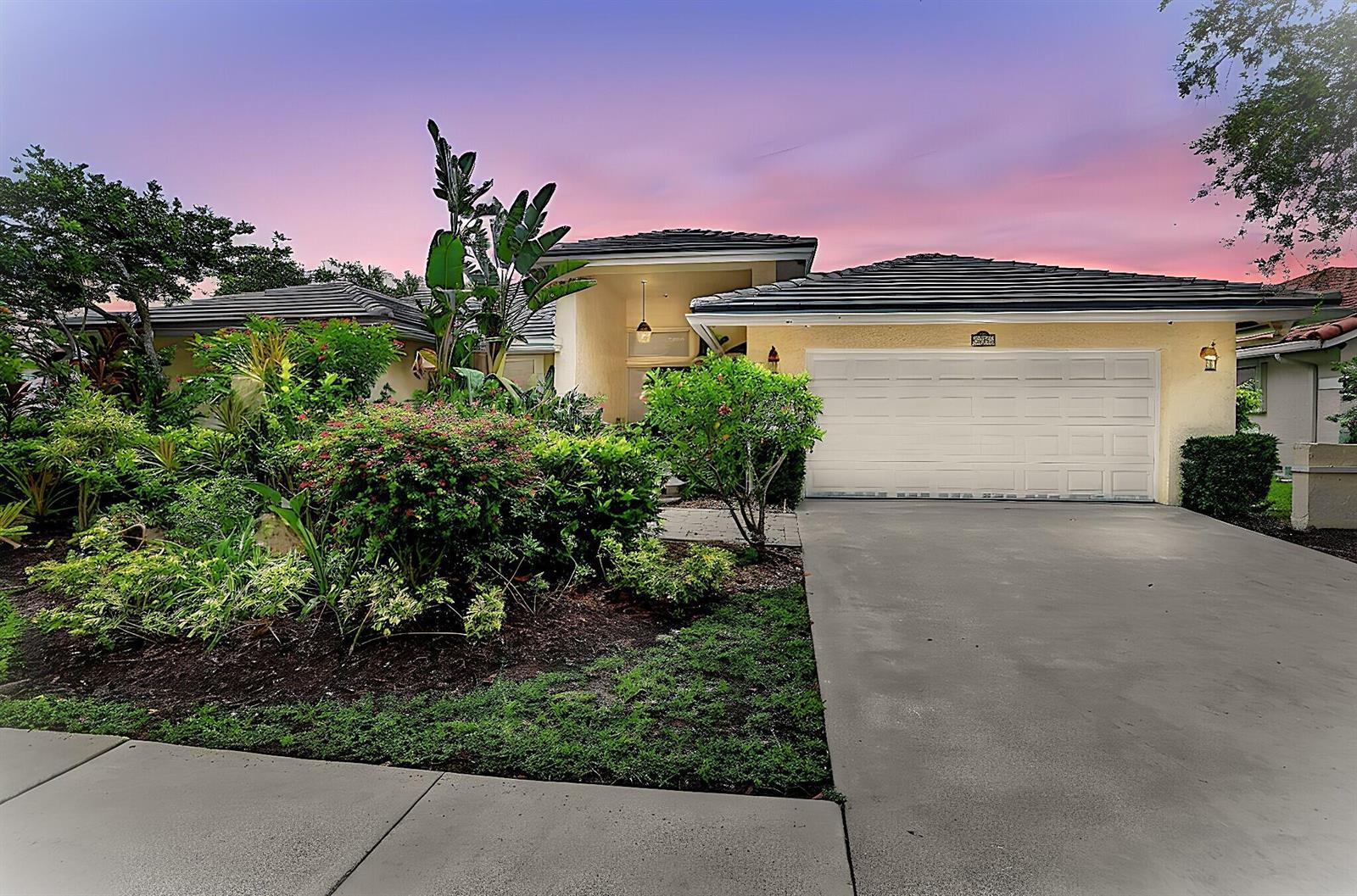 A single-story house with a two-car garage and lush landscaping under a sunset sky — 1230 Fairfax Court, Weston FL 33326, WESTON, FL