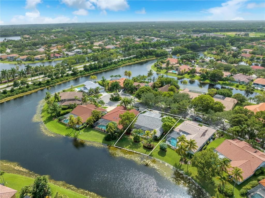 A swimming pool viewed from a screened-in lanai overlooking a lake and palm trees — 1230 Fairfax Court, Weston FL 33326, WESTON, FL