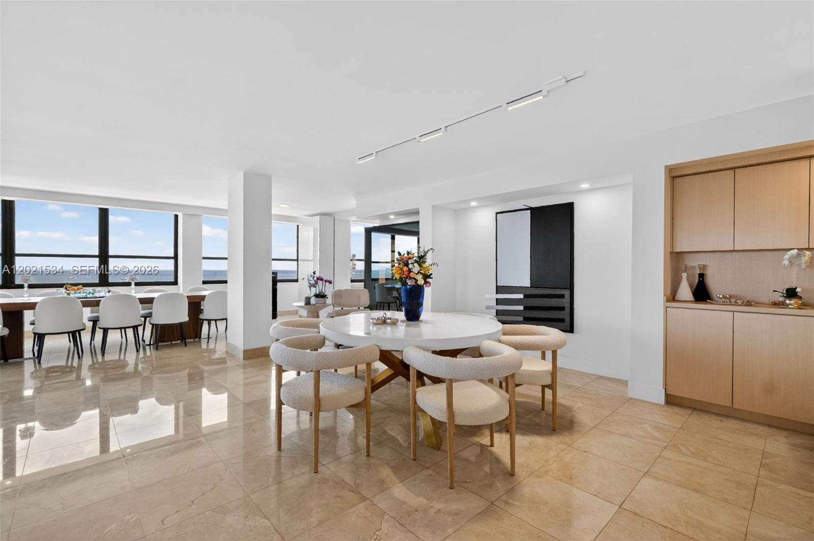 A dining area features a round table with cream chairs and marble tile flooring — 2 Grove Isle Dr # 802, Miami FL 33133, MIAMI, FL