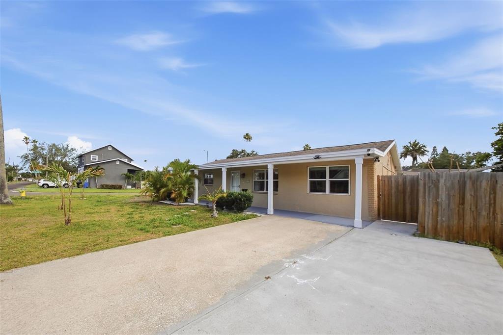 A single-story house with a concrete driveway, covered porch, and wooden fence — 1565 CONNECTICUT AVENUE NE, ST PETERSBURG, FL