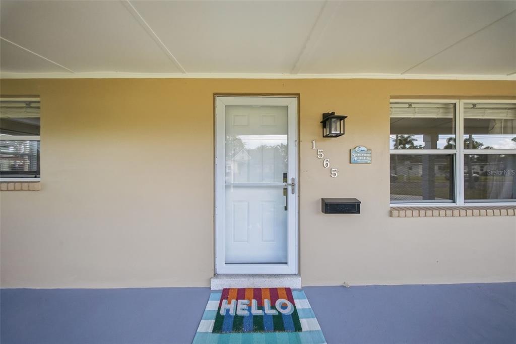 A front entrance features a white storm door, a house number, and a colorful doormat — 1565 CONNECTICUT AVENUE NE, ST PETERSBURG, FL