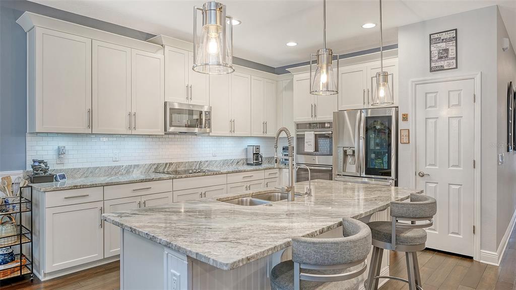A kitchen with white cabinets, granite countertops, a center island, and stainless steel appliances — 766 129TH STREET NE, BRADENTON, FL