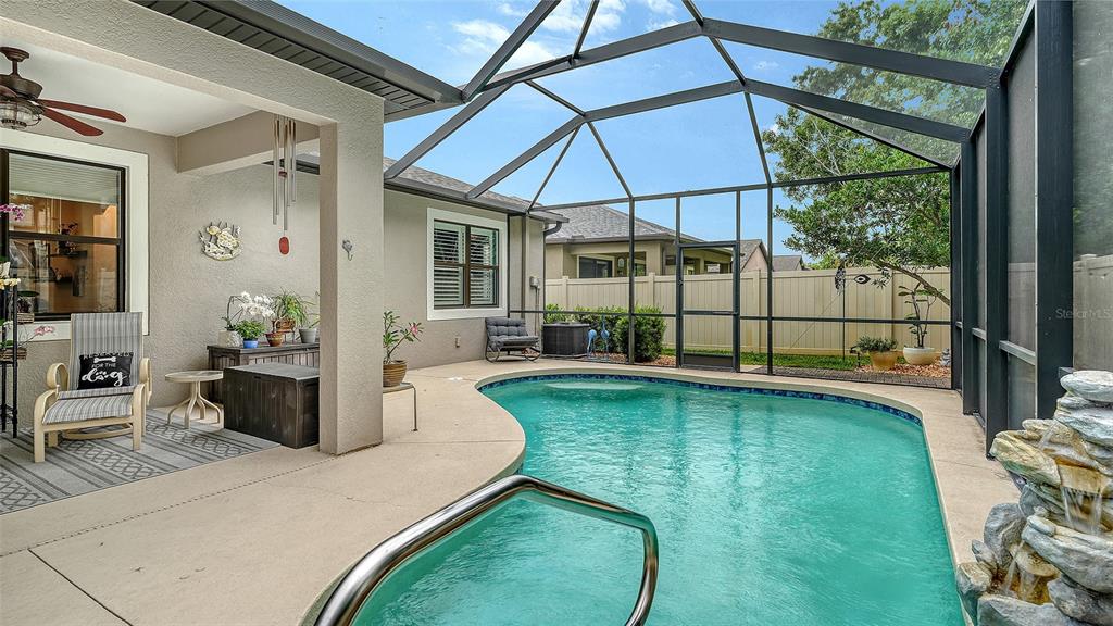A screened-in patio features a swimming pool, a rock waterfall, and a covered seating area — 766 129TH STREET NE, BRADENTON, FL
