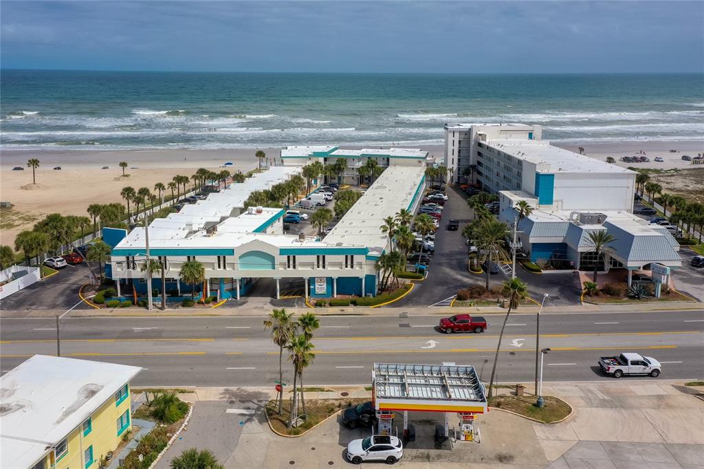 An aerial view shows a beachfront hotel complex situated next to a gas station — 935 S ATLANTIC AVENUE UNIT 165, DAYTONA BEACH, FL