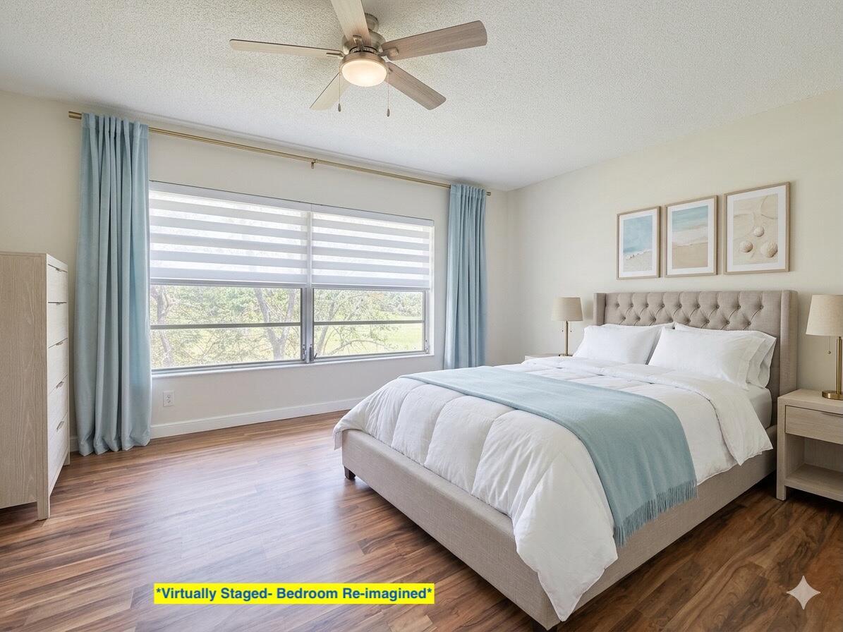 This is a virtually staged bedroom featuring light wood flooring, a bed, and blue curtains — 2800 N Palm Aire Drive Unit 404, Pompano Beach FL 33069, POMPANO BEACH, FL