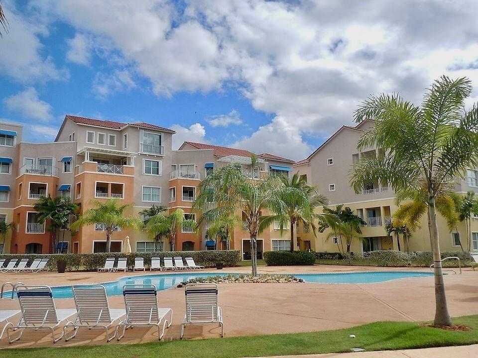 A multi-story apartment complex overlooks a swimming pool with lounge chairs on the deck — 170 CANDELERO DRIVE UNIT 209B, HUMACAO, PR 00791, PR
