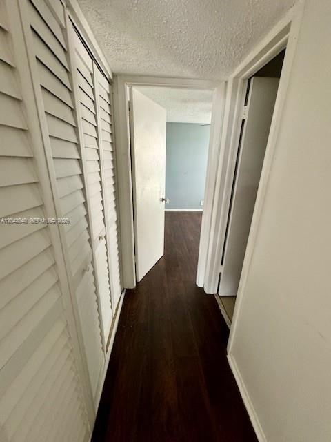 A hallway with louvered closet doors leads to a room with dark wood-look flooring — 2029 NW 46th Ave # E202, Lauderhill FL 33313, LAUDERHILL, FL