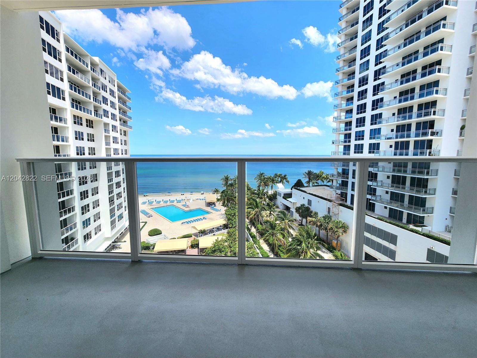 A balcony view overlooks a swimming pool, beach, and ocean between two high-rise buildings — 3505 S Ocean Dr # 821, Hollywood FL 33019, HOLLYWOOD, FL