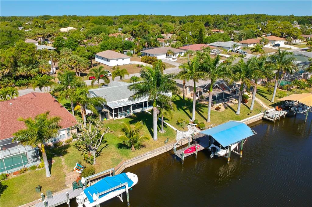 An aerial view shows a waterfront house with a boat lift and a private dock — 18289 WOLBRETTE CIRCLE, PORT CHARLOTTE, FL