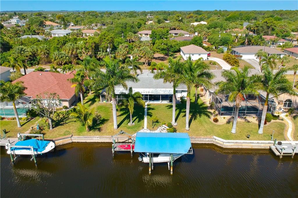 An aerial view shows a waterfront house with a boat lift and dock on a canal — 18289 WOLBRETTE CIRCLE, PORT CHARLOTTE, FL
