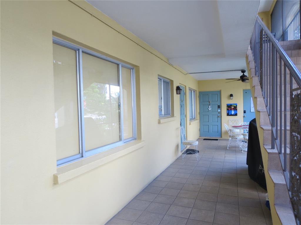 A tiled outdoor walkway features yellow walls, blue entry doors, and a metal staircase — 615 S PALM AVENUE UNIT 4, SARASOTA, FL