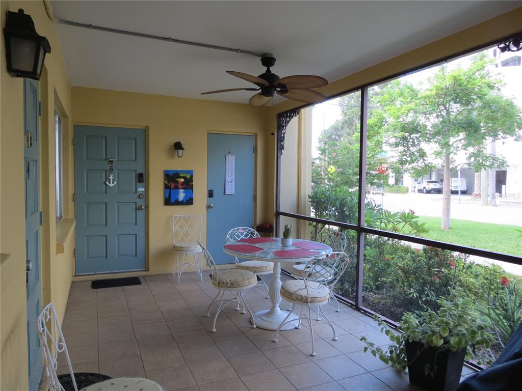 A screened-in porch features tiled flooring, a ceiling fan, a bistro set, and blue doors — 615 S PALM AVENUE UNIT 4, SARASOTA, FL