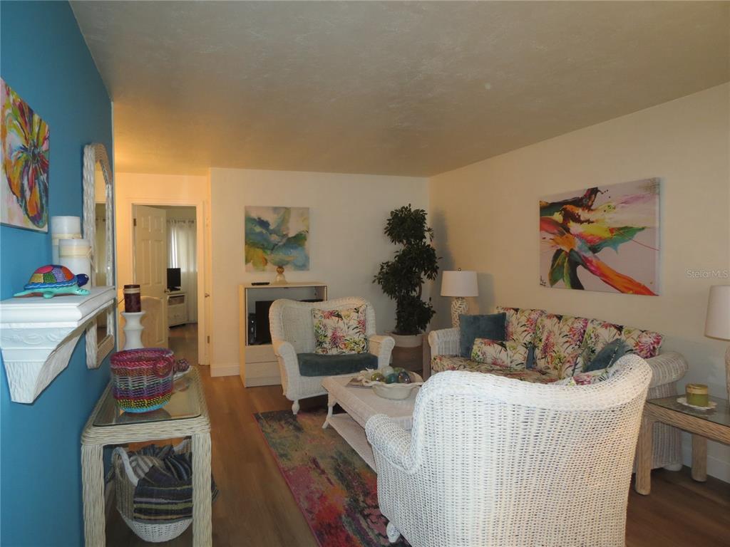 A living room features white wicker furniture, a colorful area rug, and vibrant wall art — 615 S PALM AVENUE UNIT 4, SARASOTA, FL