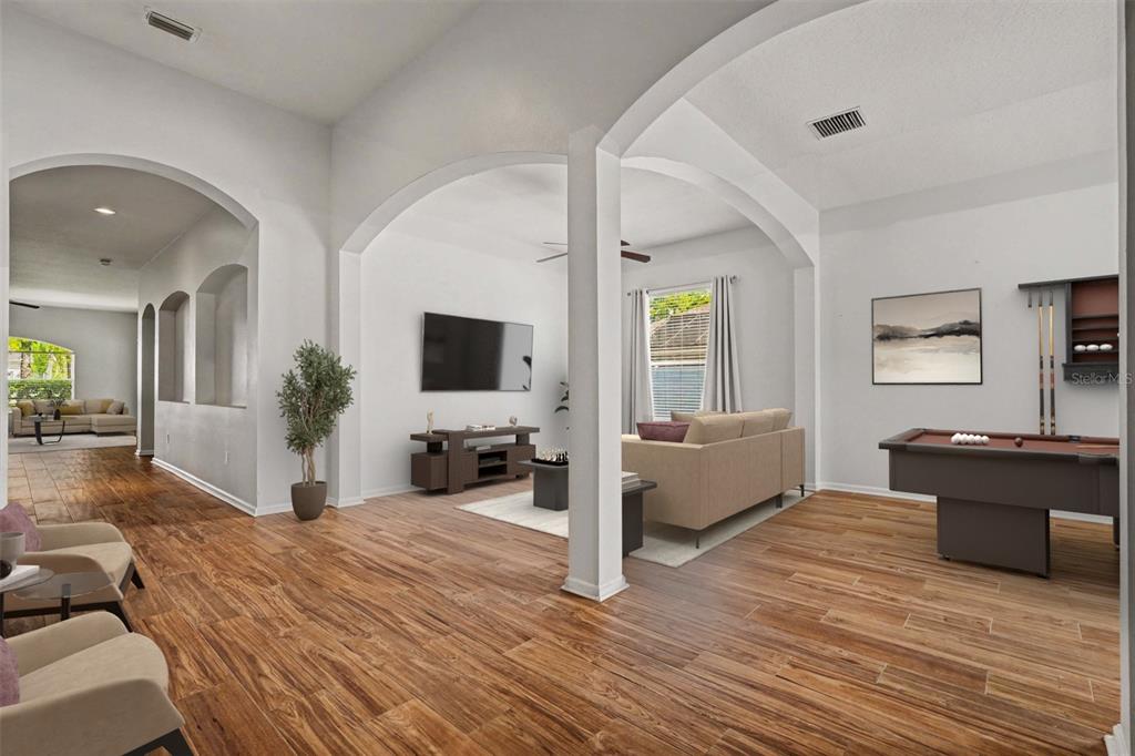 An open-concept living area features wood-look tile flooring, arched entryways, a pool table, and furniture — 20835 RIVERFOREST DRIVE, LAND O LAKES, FL