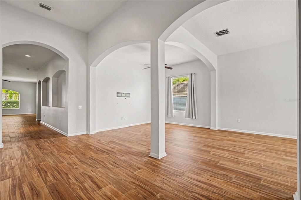 An interior view of an open-concept living area with arched doorways and wood-look tile flooring — 20835 RIVERFOREST DRIVE, LAND O LAKES, FL