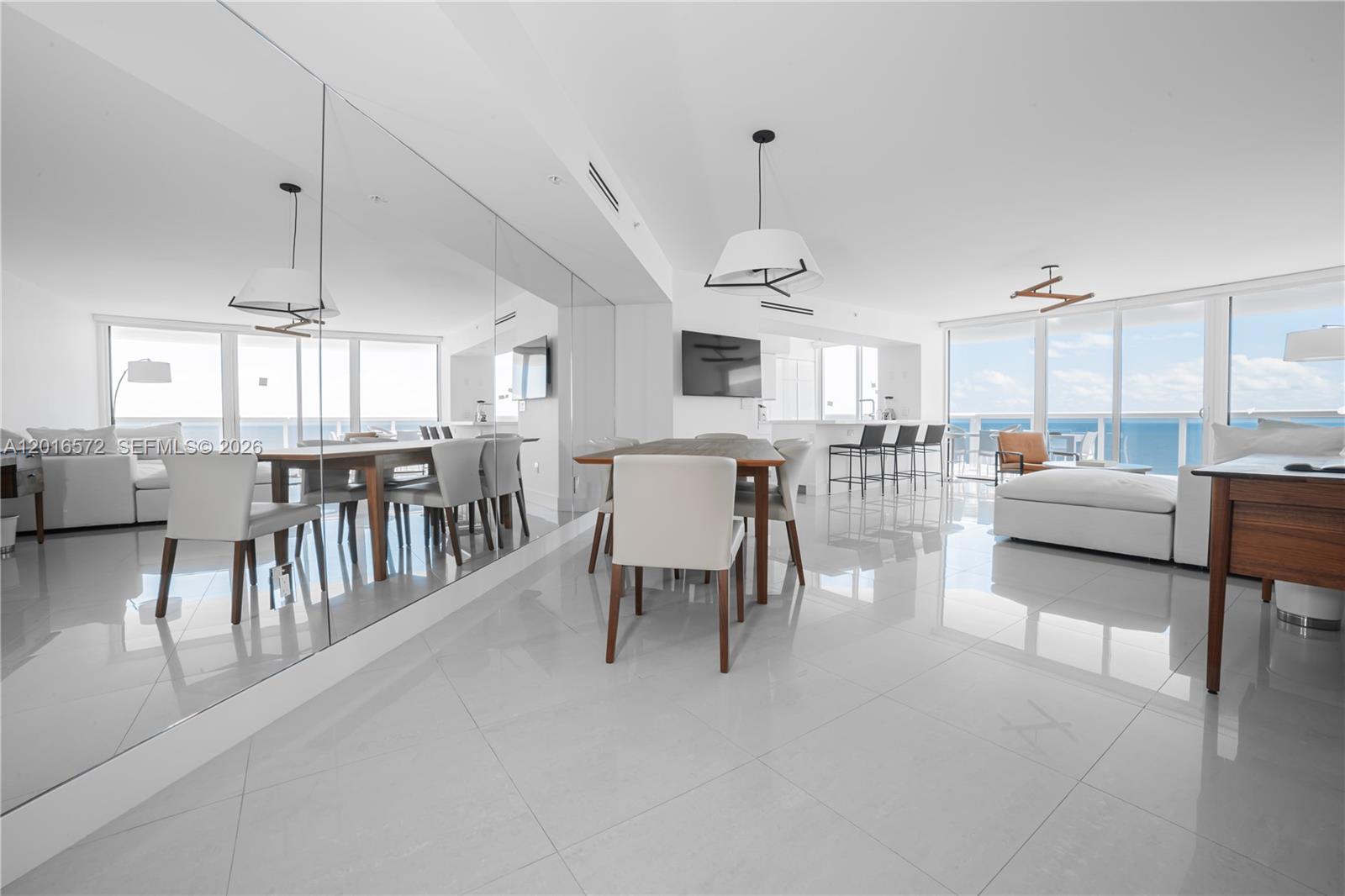A bright, open-concept dining and living area features white tile floors and ocean views — 6301 Collins Ave # 1102, Miami Beach FL 33141, MIAMI BEACH, FL
