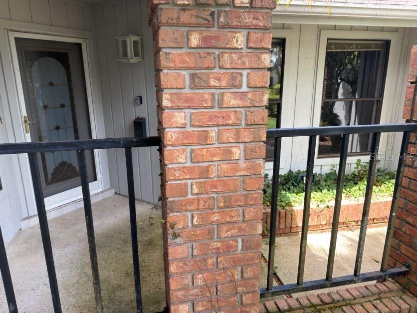 A brick pillar stands on a concrete porch with black metal railings and a door — 2620 BENT HICKORY CIRCLE, LONGWOOD, FL