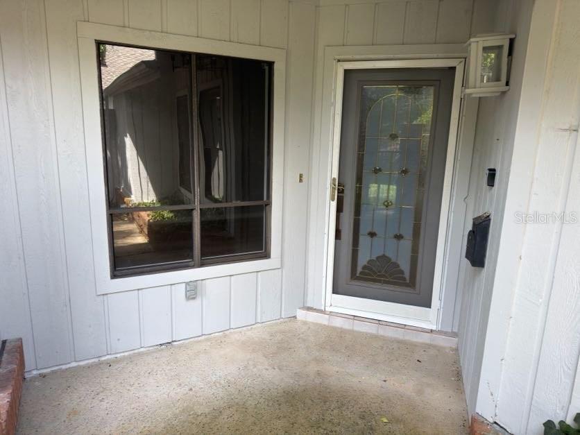 A front porch with a large window and a glass-paneled door with a storm door — 2620 BENT HICKORY CIRCLE, LONGWOOD, FL
