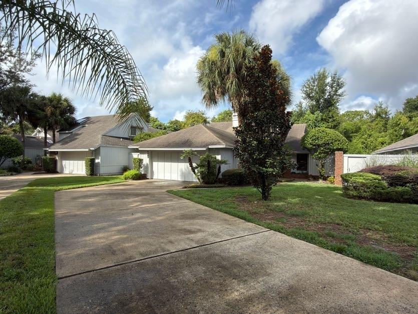 A concrete driveway leads to a single-story house with a garage and palm trees — 2620 BENT HICKORY CIRCLE, LONGWOOD, FL