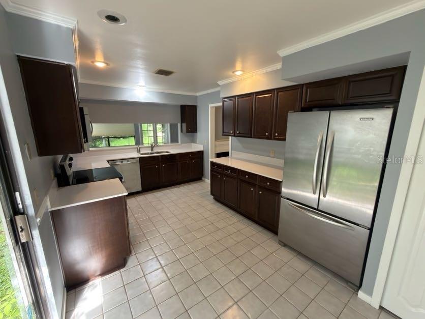 A kitchen with dark wood cabinets, stainless steel appliances, and light-colored tile flooring — 2620 BENT HICKORY CIRCLE, LONGWOOD, FL
