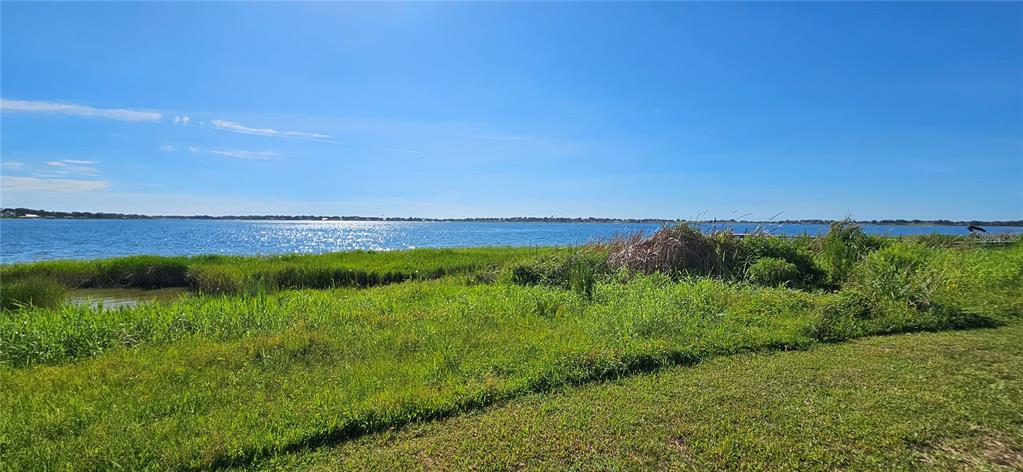 A grassy shoreline leads to a large lake under a clear blue sky — US HIGHWAY 630 W, FROSTPROOF, FL