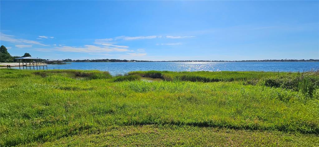 A grassy field leads to a lake with several small docks under a blue sky — US HIGHWAY 630 W, FROSTPROOF, FL