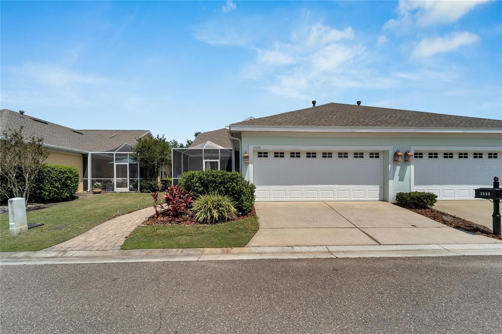 A single-story duplex with a two-car garage, a screened-in patio, and a paved walkway — 5508 GOLDEN ISLES DRIVE, APOLLO BEACH, FL