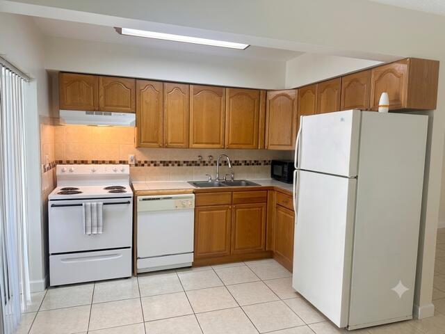 A kitchen features wood cabinets, white appliances, a tiled backsplash, and light-colored floor tiles — 1511 SE 23rd Avenue # 1, Pompano Beach FL 33062, POMPANO BEACH, FL