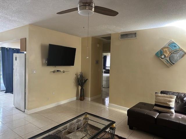 A living room features a ceiling fan, wall-mounted television, tiled floors, and a leather sofa — 1511 SE 23rd Avenue # 1, Pompano Beach FL 33062, POMPANO BEACH, FL
