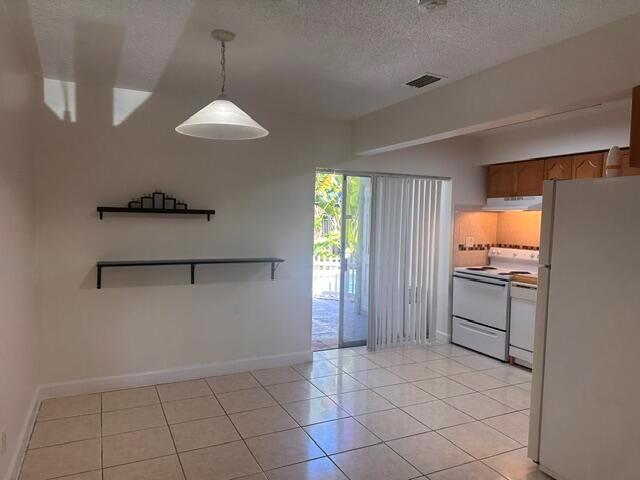 A dining area with tile floors, two wall shelves, and an adjacent kitchen with white appliances — 1511 SE 23rd Avenue # 1, Pompano Beach FL 33062, POMPANO BEACH, FL