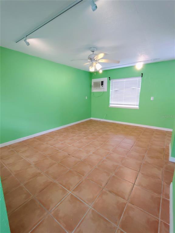 An empty room with bright green walls, terracotta tile flooring, and a ceiling fan — 115 145TH AVENUE E UNIT 4, MADEIRA BEACH, FL