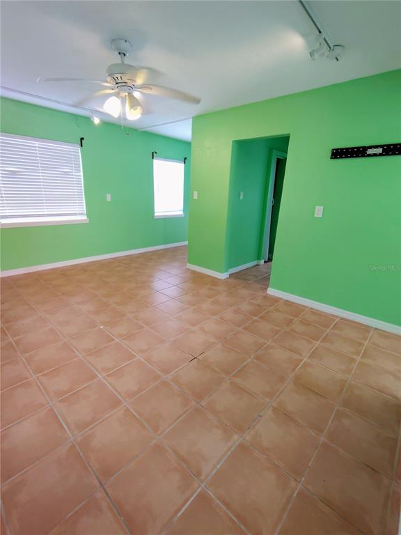 A room with bright green walls, tan tile flooring, and a ceiling fan — 115 145TH AVENUE E UNIT 4, MADEIRA BEACH, FL