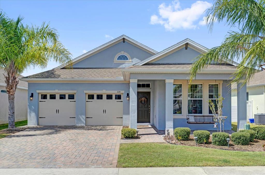 A light blue single-story house features a two-car garage, a covered porch, and palm trees — 224 VENETIAN PALMS BOULEVARD, NEW SMYRNA BEACH, FL
