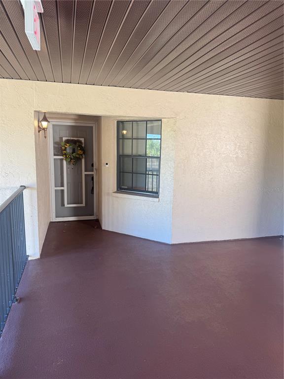 A covered entryway features a brown floor, a gray front door, and a window — 23465 HARBORVIEW ROAD UNIT 201, PUNTA GORDA, FL