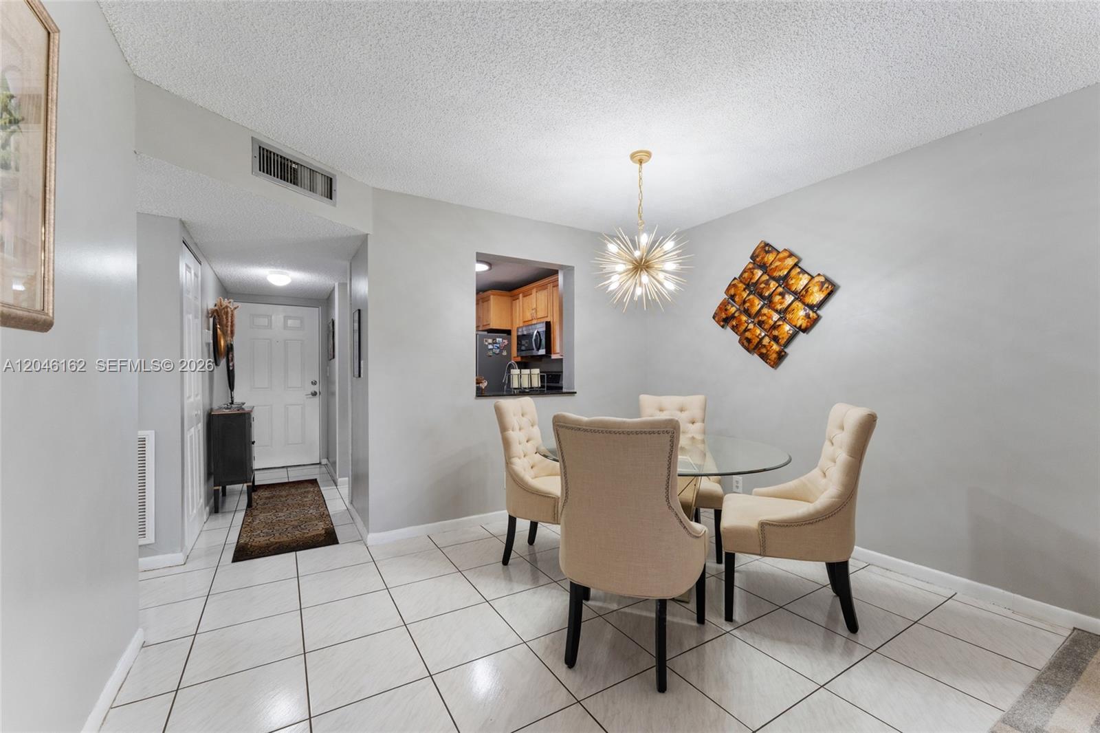 A dining area features a glass table, four tufted chairs, and a starburst chandelier — 8550 N Sherman Cir # 108, Miramar FL 33025, MIRAMAR, FL
