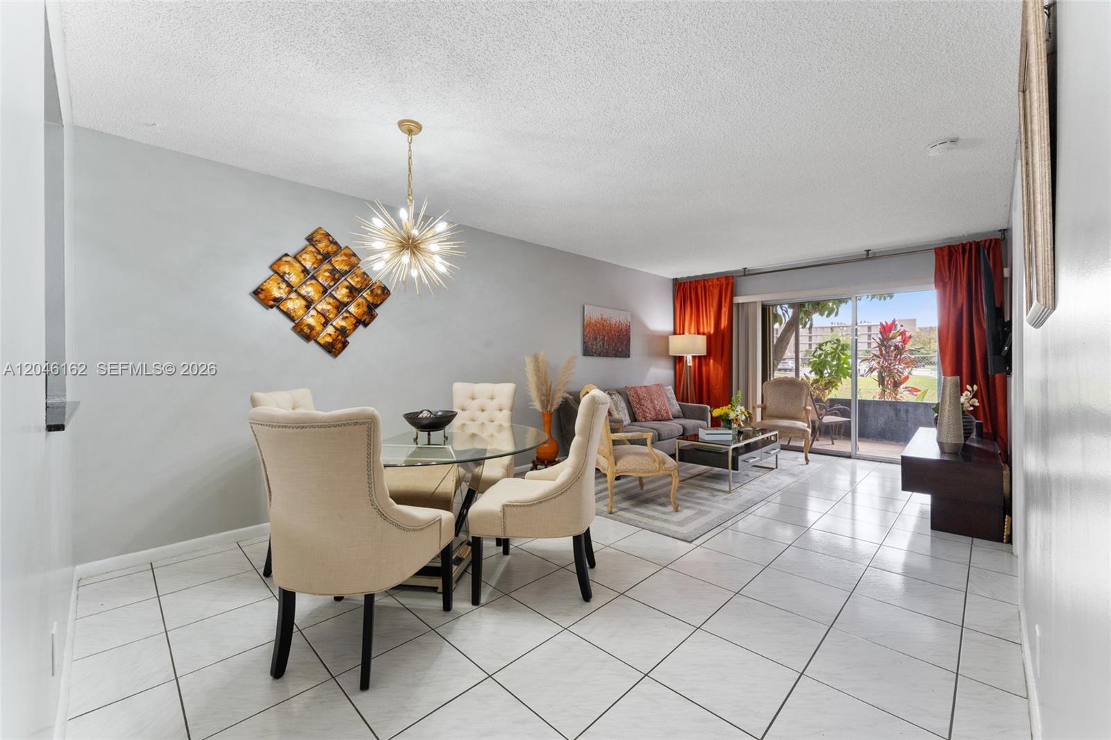 A dining area with a glass table and chandelier sits adjacent to a living room — 8550 N Sherman Cir # 108, Miramar FL 33025, MIRAMAR, FL