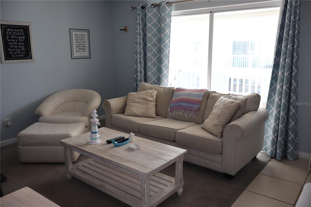 A living room features a beige sofa, a matching armchair with ottoman, and a wooden coffee table — 180 FLAGLER LANE UNIT 26, COCOA BEACH, FL