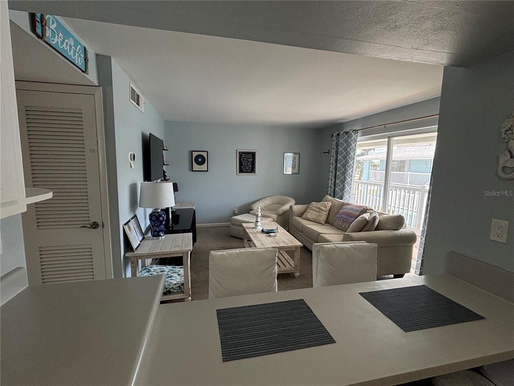 A living room with a sofa, armchair, coffee table, and a view of a balcony — 180 FLAGLER LANE UNIT 26, COCOA BEACH, FL