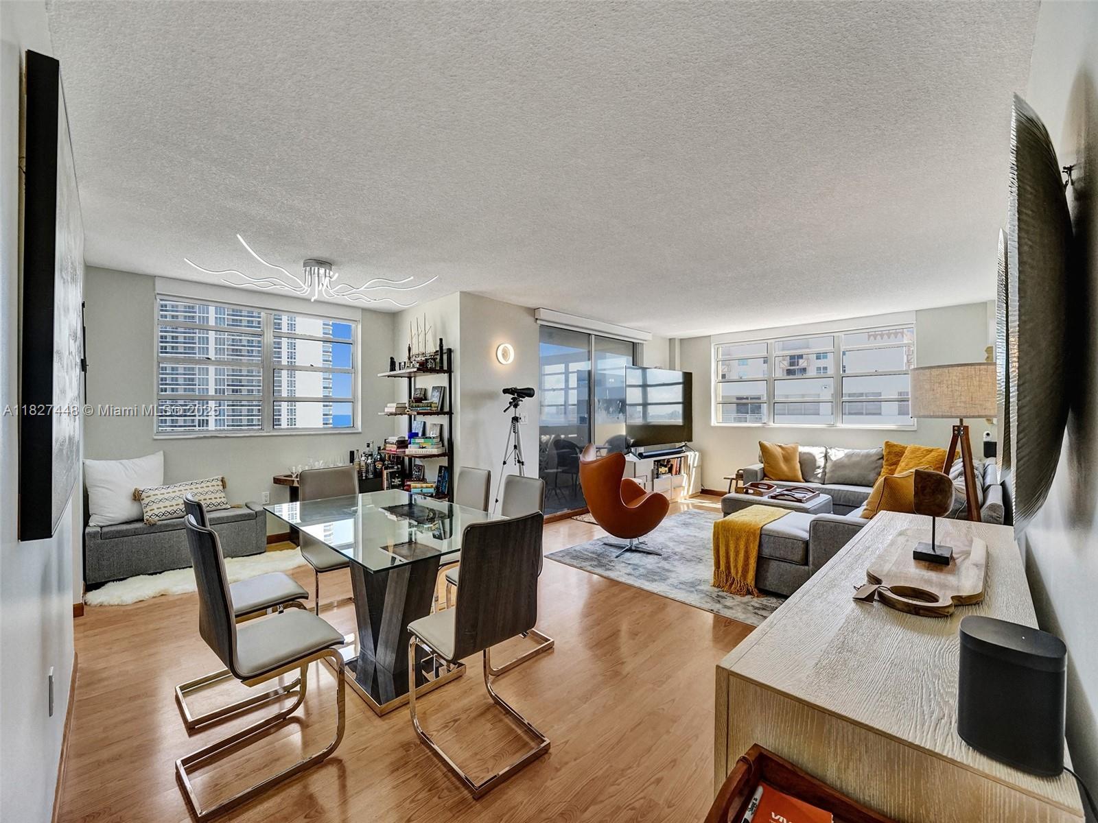 A living and dining area features wood flooring, a glass table, and large windows — 1833 S Ocean Dr # 1702, Hallandale Beach FL 33009, HALLANDALE BEACH, FL