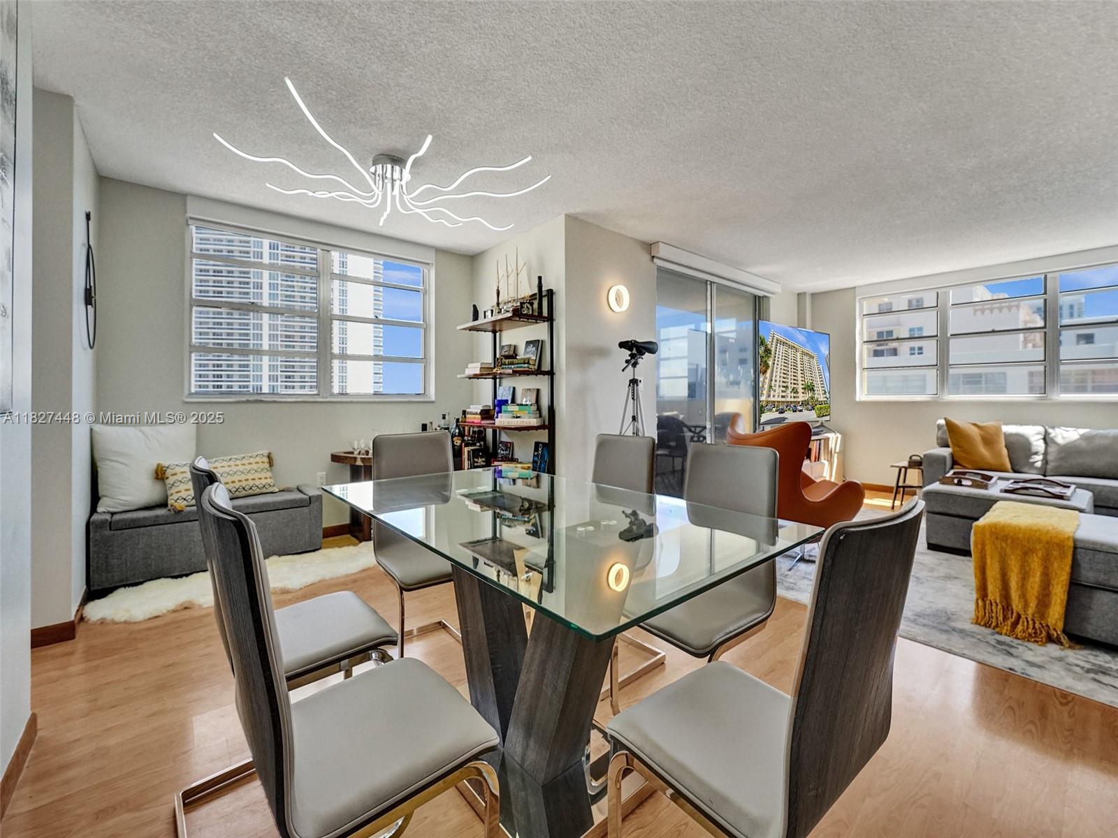 A dining area with a glass table and chairs sits adjacent to a living room — 1833 S Ocean Dr # 1702, Hallandale Beach FL 33009, HALLANDALE BEACH, FL