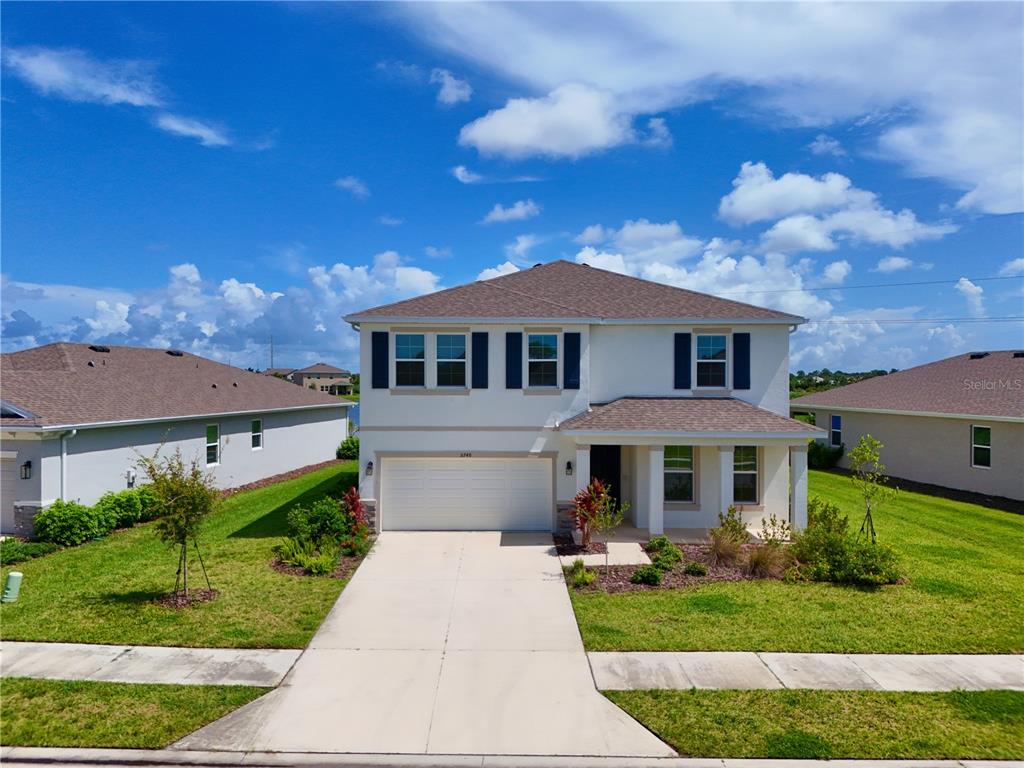 A two-story suburban house with a white exterior, a two-car garage, and a lawn — 5748 WOODLAND SAGE DRIVE, SARASOTA, FL