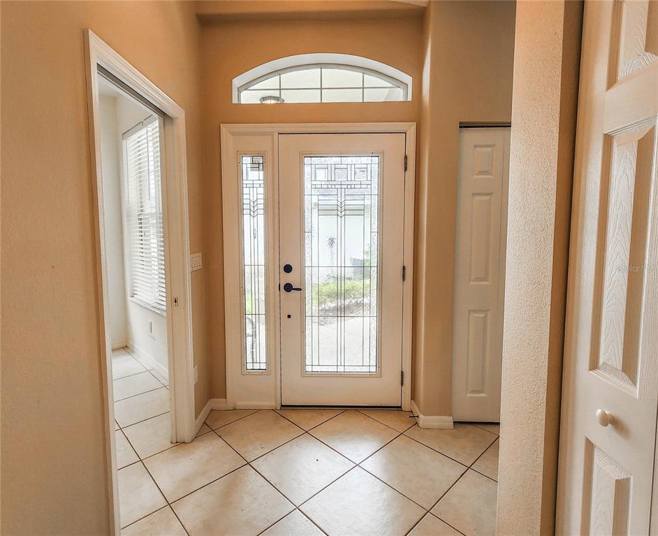 An entryway features a tiled floor, a white front door with glass, and a side window — 44 CROSSTIE COURT, PALM COAST, FL