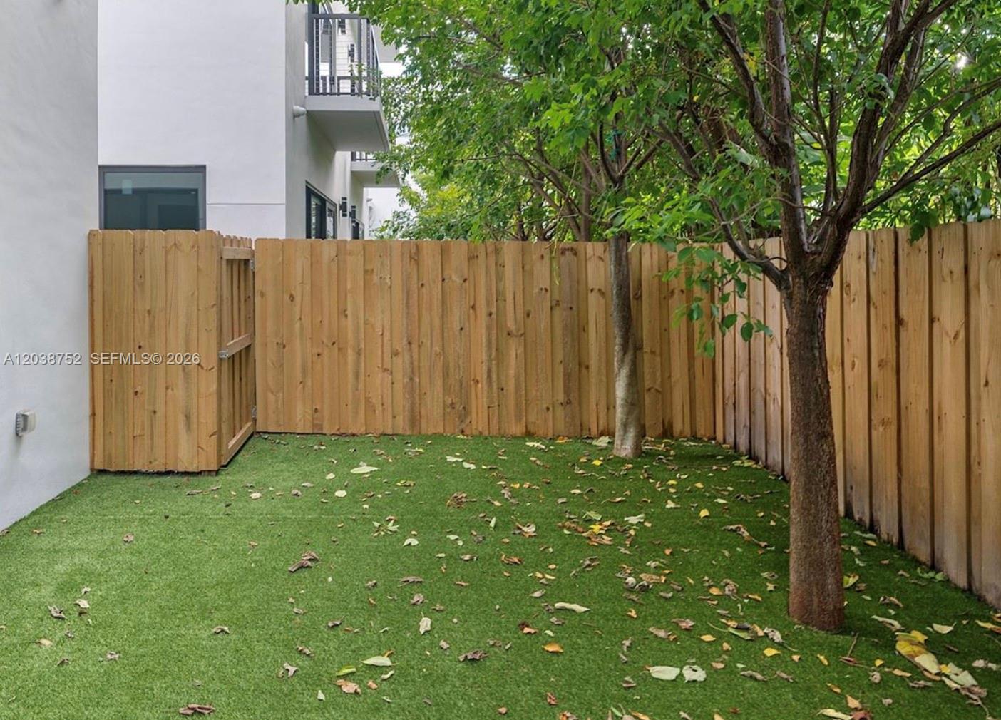 A small backyard features artificial turf, a wooden privacy fence, and two trees — 3374 Perry Frow Dr # B, Miami FL 33133, MIAMI, FL