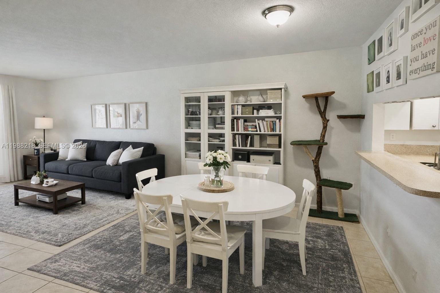 A dining area with a white table and chairs sits beside a living room — 8225 SW 29th St # 102, Miramar FL 33025, MIRAMAR, FL