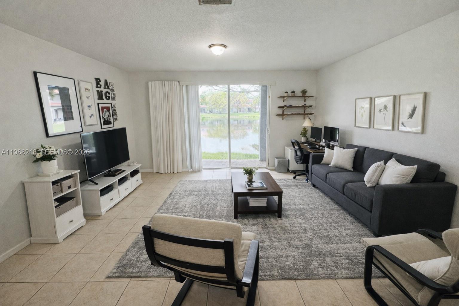 A living room features a dark sofa, a coffee table, and a view of water — 8225 SW 29th St # 102, Miramar FL 33025, MIRAMAR, FL