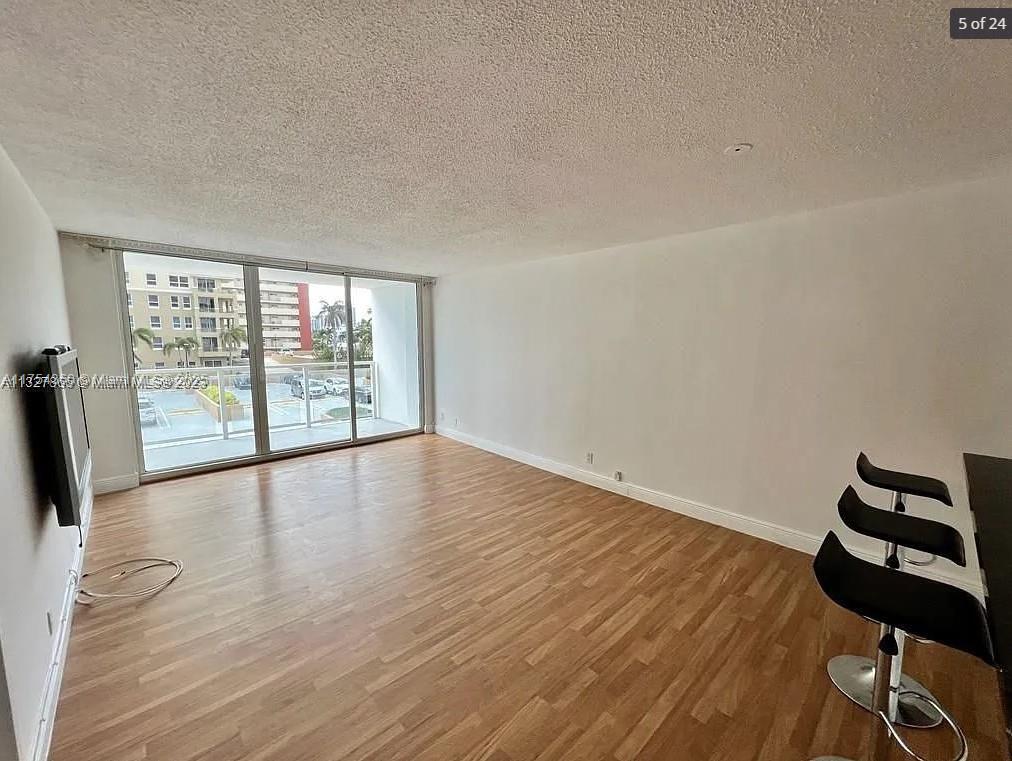 An empty room features light wood-look flooring, white walls, and a sliding glass door to a balcony — 2030 S Ocean Dr # 211, Hallandale Beach FL 33009, HALLANDALE BEACH, FL